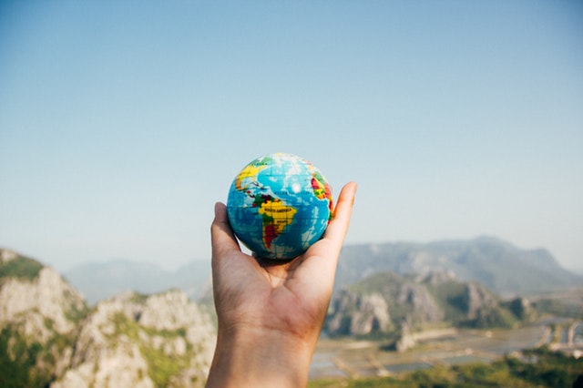 hand holding a globe with a beautiful scenery